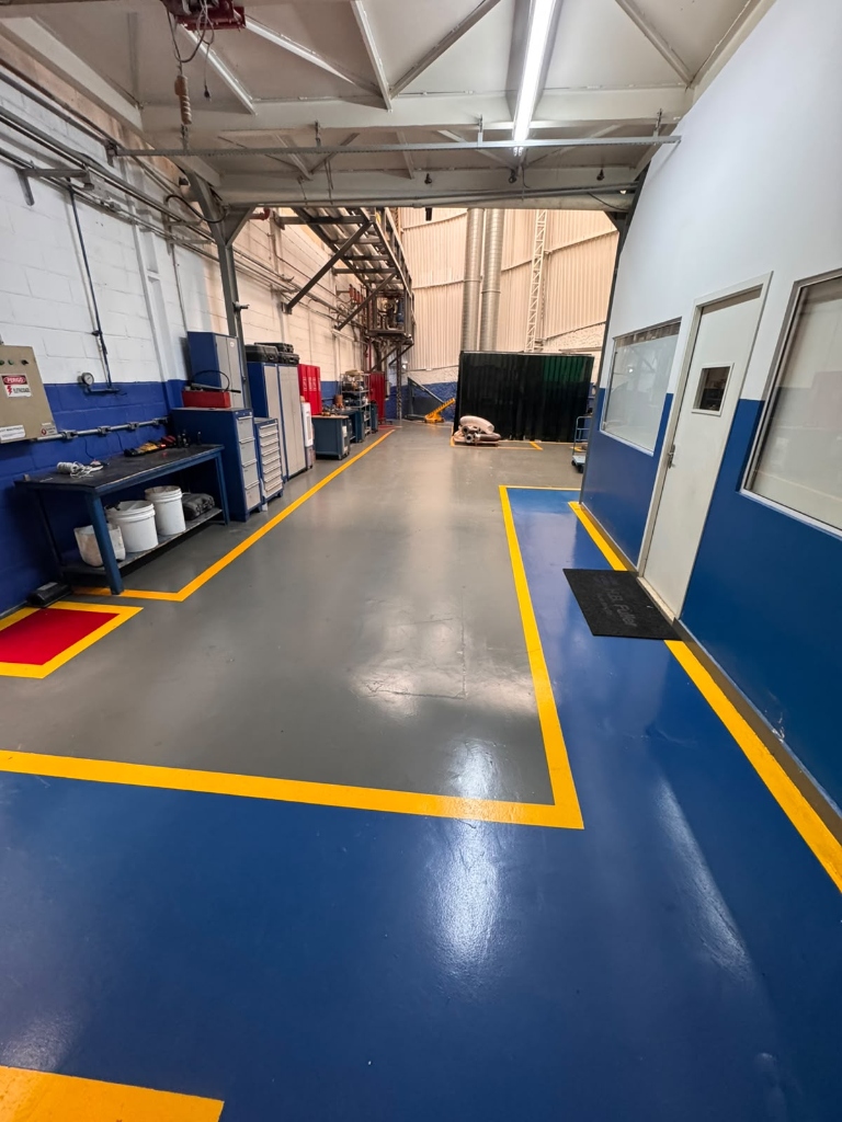 Piso Epóxi Industrial - Galpão com sinalização amarela e parede azul